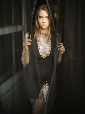 Modelka prezentuje najnowsze zdjęcie z portfolio KaBoom, przedstawiające zasłona, siateczka, sukienka, piercing, okno